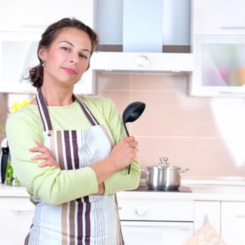 Young woman with a smug expression holding a ladle in the kitchen