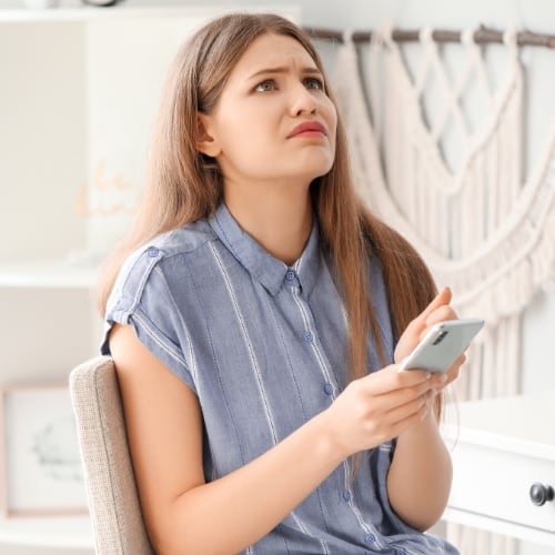 young woman with her phone looking worried and stressed