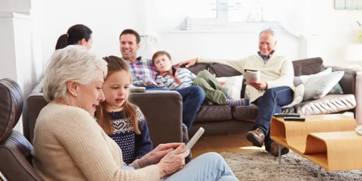 Multi-generational family at home in a living room, sitting on couches and chairs with different quiet activities and conversations taking place
